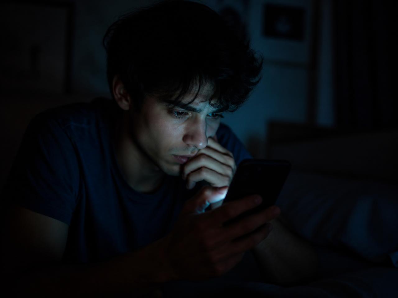 Persona mirando el móvil en una habitación oscura